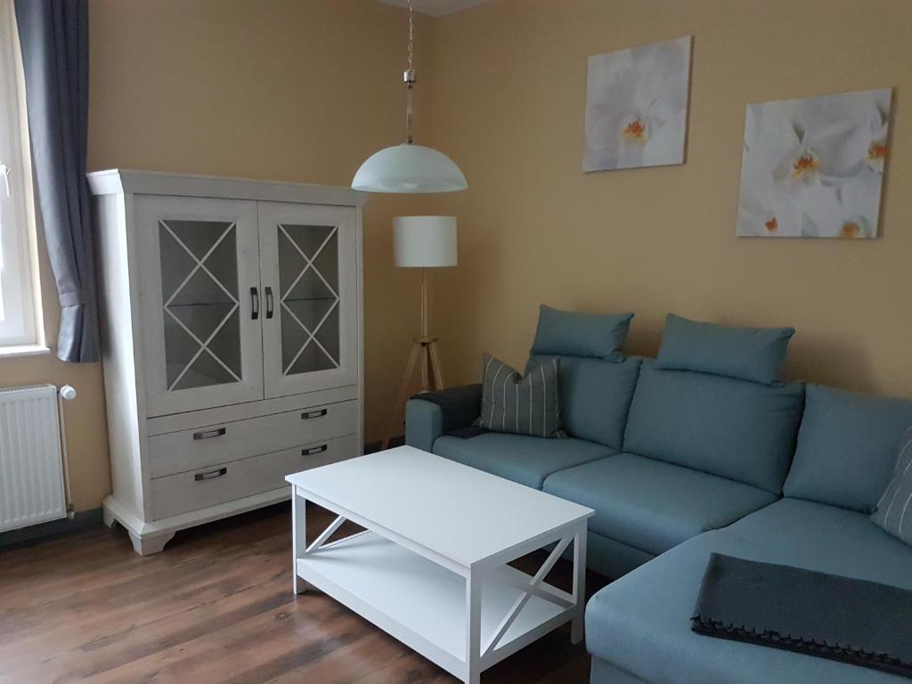 ein Wohnzimmer mit einem blauen Sofa und einem Tisch in der Unterkunft Ferienwohnungen Harz - Wieda in Wieda