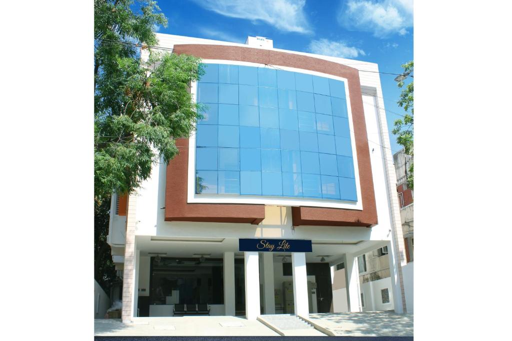 a large glass building with a blue sign on it at Staylite Suites in Chennai
