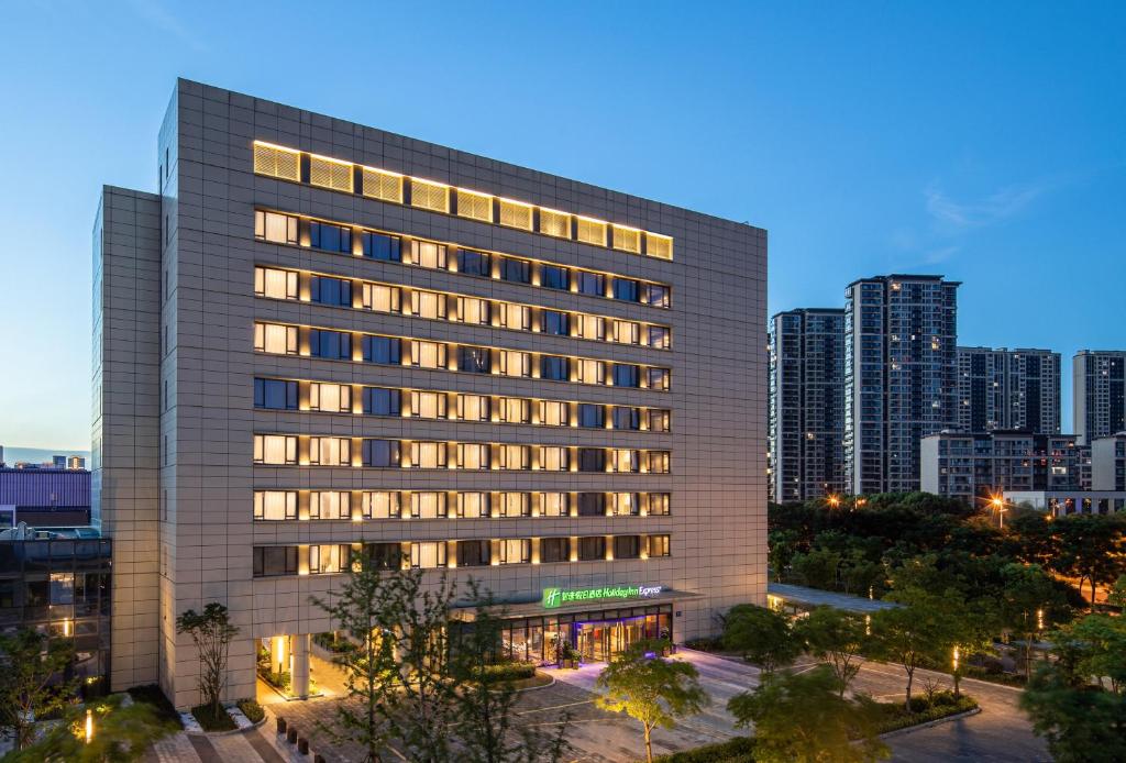 um edifício alto com luzes acesas numa cidade em Holiday Inn Express Wuxi Taihu New City, an IHG Hotel em Wuxi