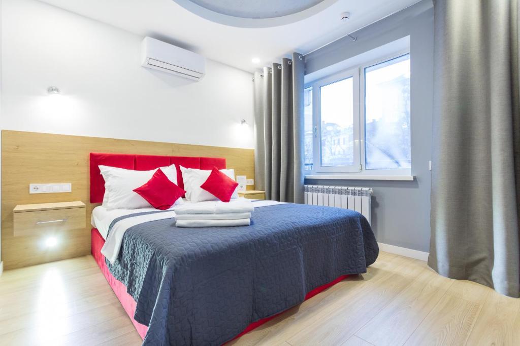 Schlafzimmer mit einem Bett mit roten Kissen und einem Fenster in der Unterkunft Partner Guest House in Kiew