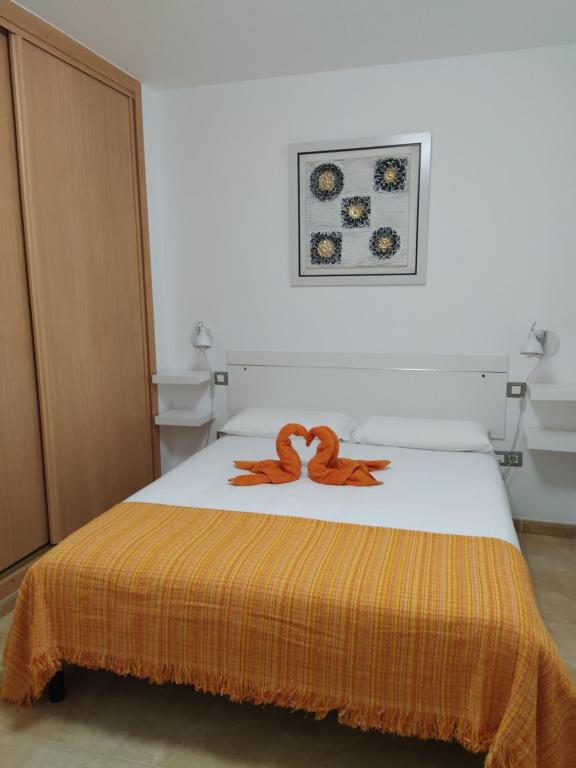 1 dormitorio con 1 cama con manta naranja en APARTMENT ORANGE FUERTEVENTURA, en Puerto del Rosario