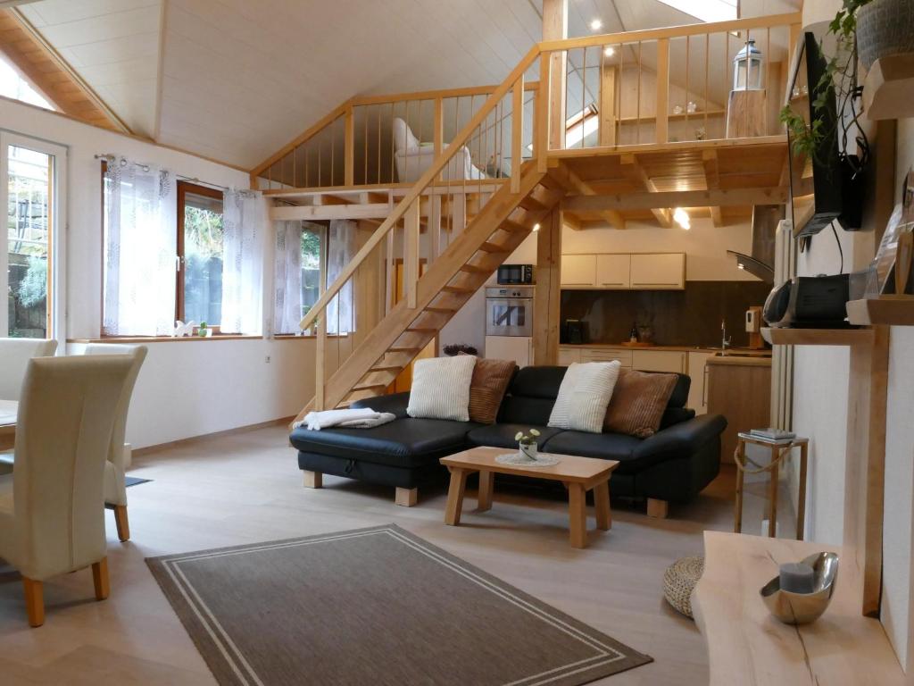 ein Wohnzimmer mit einem schwarzen Sofa und einer Treppe in der Unterkunft Ferienwohnung Lichtblick in Friesenheim
