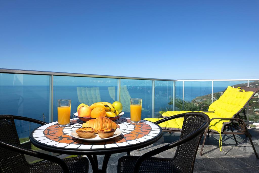 uma mesa com fruta e sumo numa varanda em Martinho Apartment View em Arco da Calheta