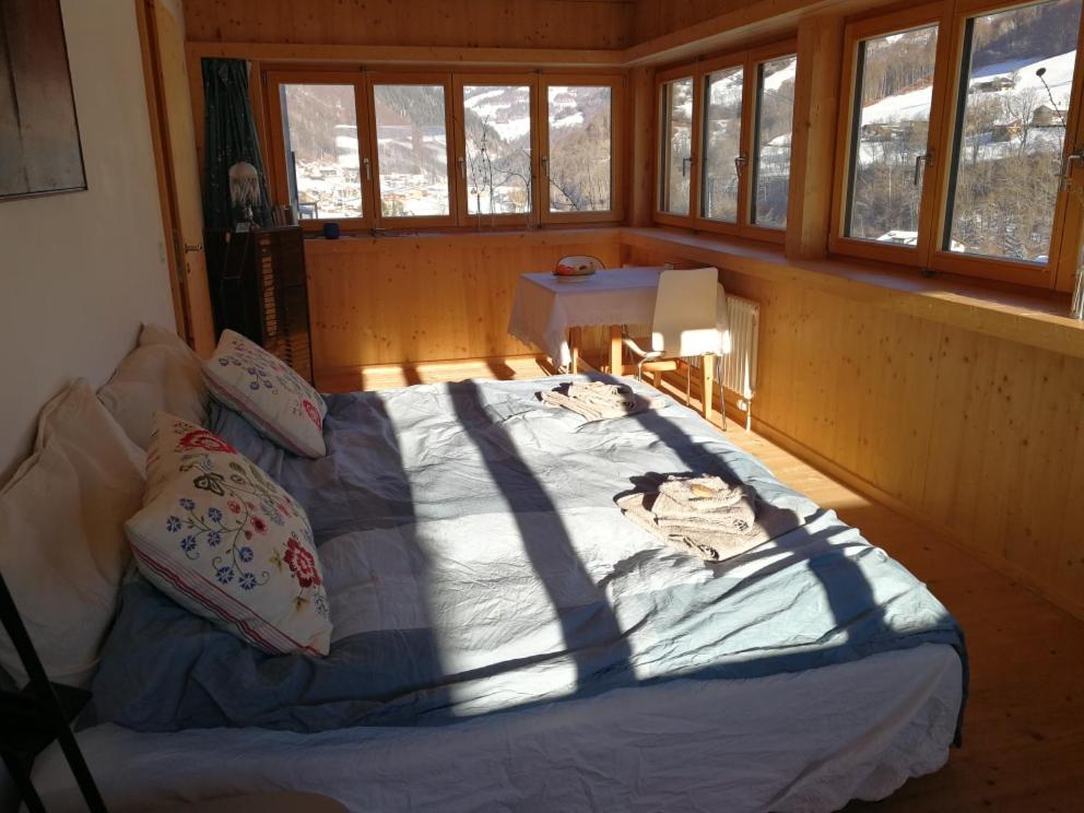 a bedroom with a large bed in a room with windows at B&B Gafaller in Jenaz