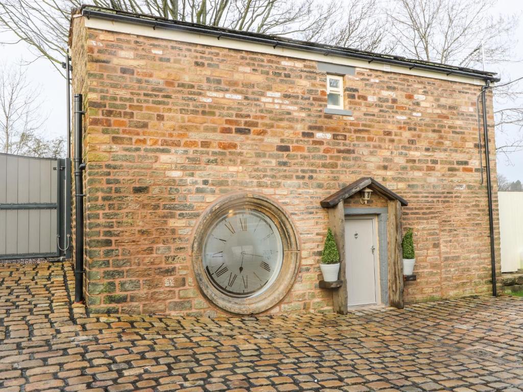 a large clock on the side of a brick building at Clock Cottage in Oldham