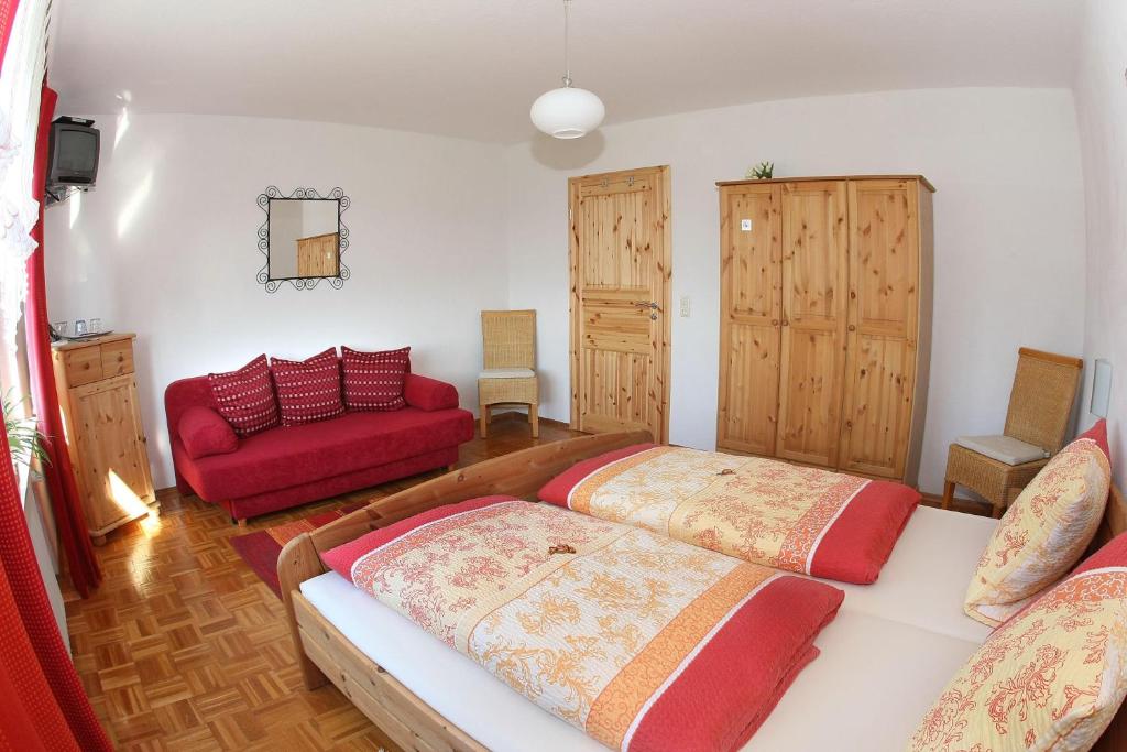 1 dormitorio con 2 camas y sofá rojo en Gaestehaus-Moeseler, en Barweiler