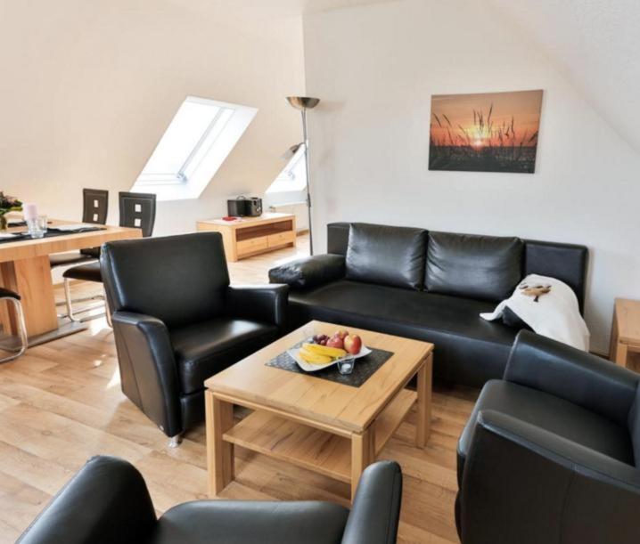 ein Wohnzimmer mit schwarzen Ledermöbeln und einem Tisch in der Unterkunft Ferienwohnung 39 Mauersegler - Urlaub in der Natur in Timmendorfer Strand