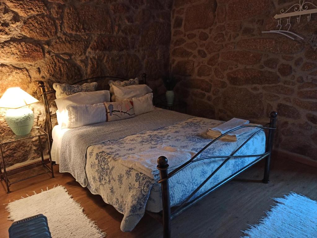 - une chambre avec un lit et un mur en pierre dans l'établissement Casa da Azenha II, à Sabugal