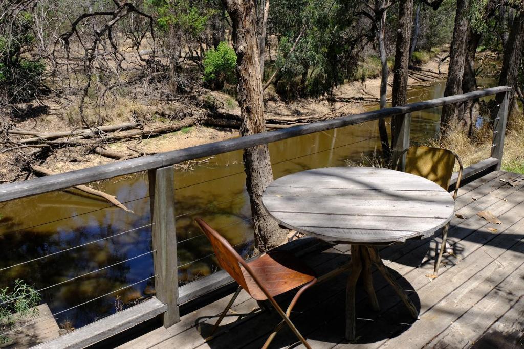 une table et des chaises sur une terrasse en bois à côté d'une rivière dans l'établissement The Laurels of Chinchilla, à Chinchilla