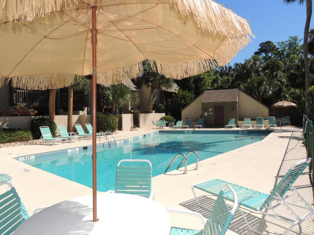 uma piscina com cadeiras e um guarda-sol em 13 Hilton Head Beach Club em Hilton Head Island