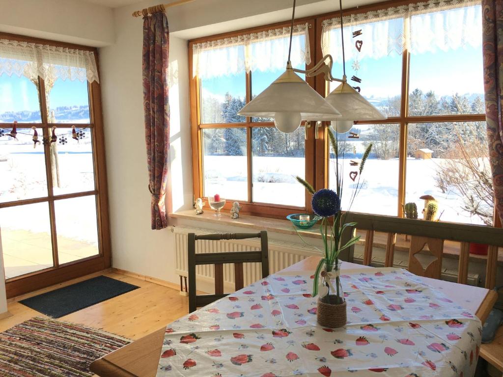 ein Esszimmer mit einem Tisch und einigen Fenstern in der Unterkunft Ferienwohnung Rottachseeblick in Sulzberg