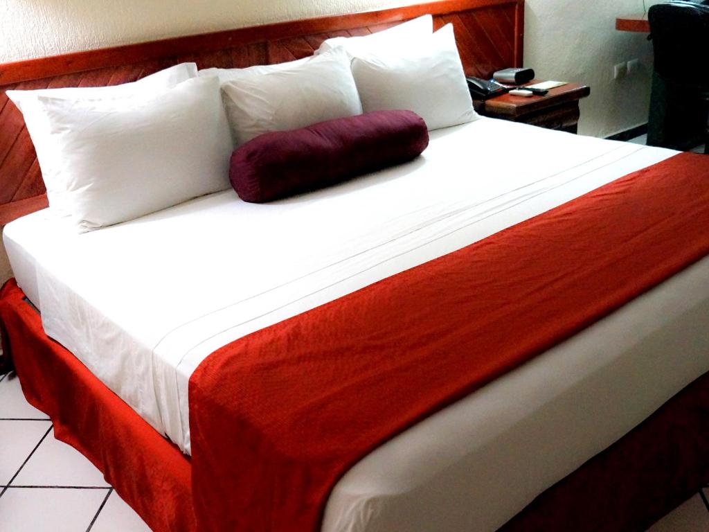 a large bed with white and red sheets and pillows at HOTEL BRISA Coatzacoalcos in Coatzacoalcos