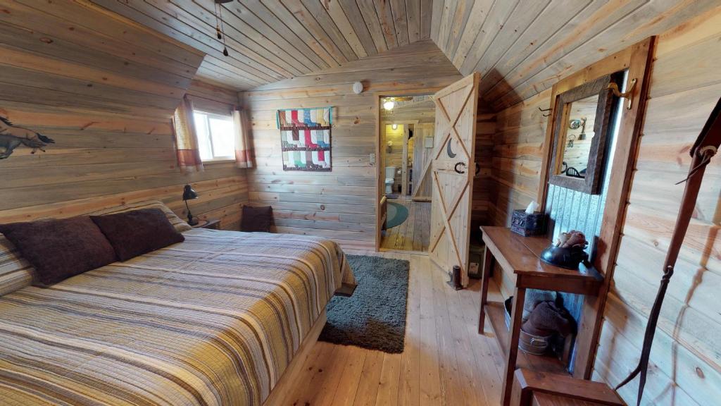 a bedroom in a log cabin with a bed and a desk at Canyonlands Barn Cabin with Loft, Full Kitchen, Dining Area for Large Groups in Verdure