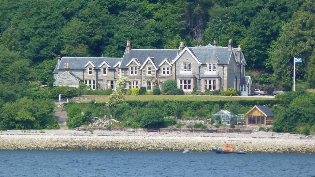 a large house on the shore of a body of water at Creag Mhor Lodge in Onich