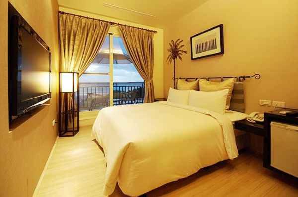 una camera da letto con un grande letto bianco e una televisione di Golden Bay Holiday Inn a Kenting