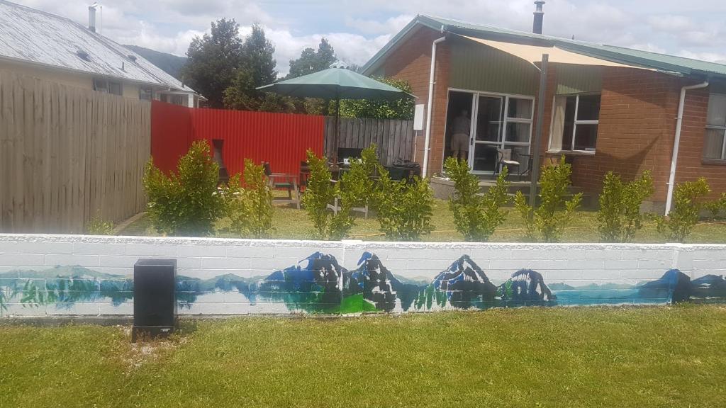 a fence with a mural on the side of a house at Little Red Riding Hood in Reefton