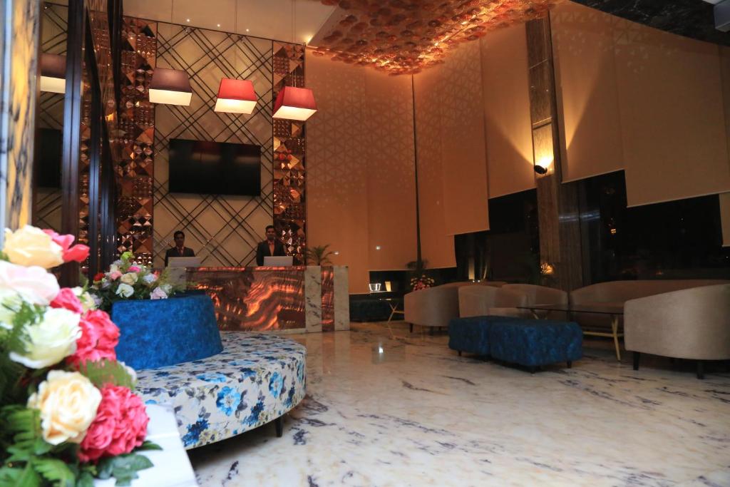 a lobby with a fireplace and a table with flowers at Pristine Hotel, Varanasi in Varanasi