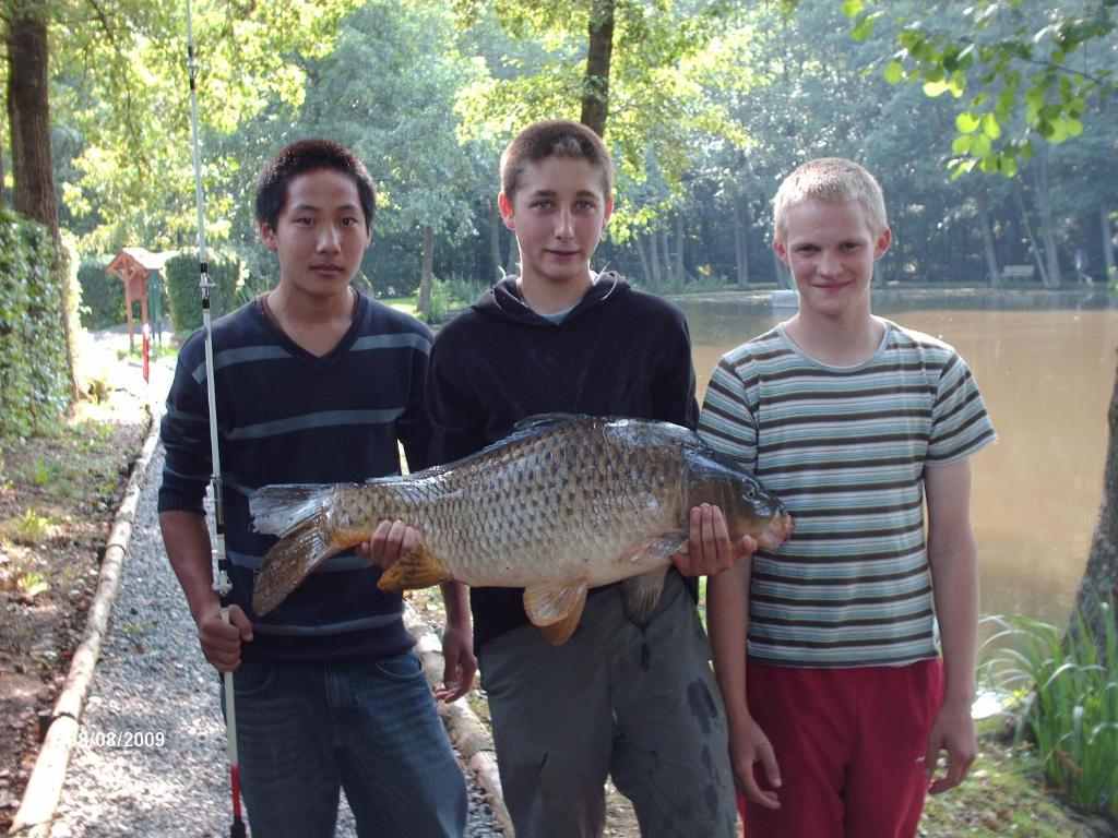 trois garçons tenant un gros poisson entre leurs mains dans l'établissement le chalet de Lola, à Saint-Michel