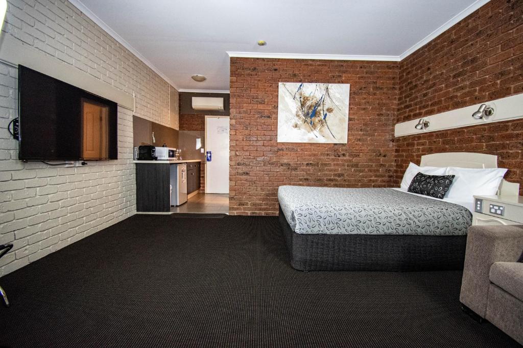 um quarto com uma cama e uma parede de tijolos em Albury Townhouse Motel em Albury