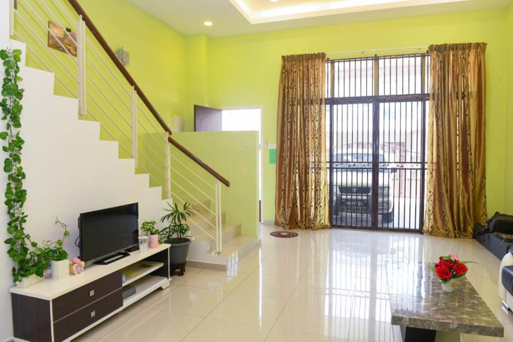 a living room with a tv and a staircase at Sky Mirror Homestay in Kuala Selangor