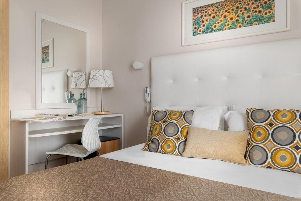 1 dormitorio con cama, escritorio y espejo en Hotel Eliseo Riccione en Riccione