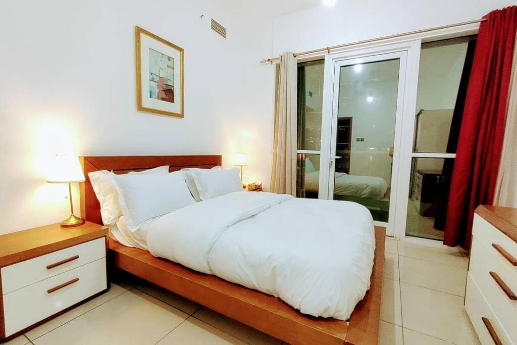 a bedroom with a white bed and a window at skynest holiday homes sea view 1 bedroom apartment dubai marina 1011 in Dubai