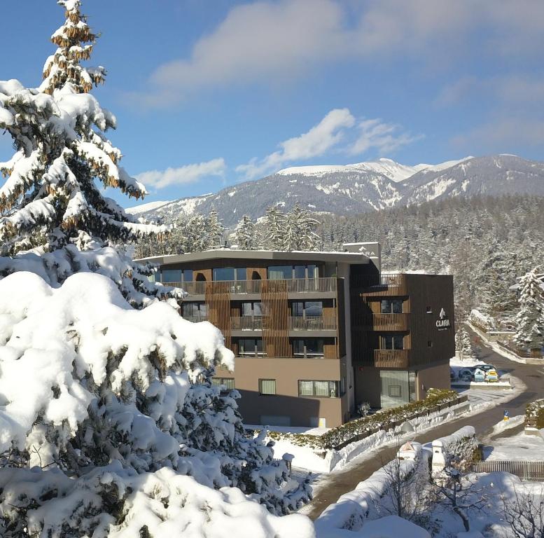 un edificio en la nieve con un árbol cubierto de nieve en B&B Boutiquehotel Clara, en Brunico