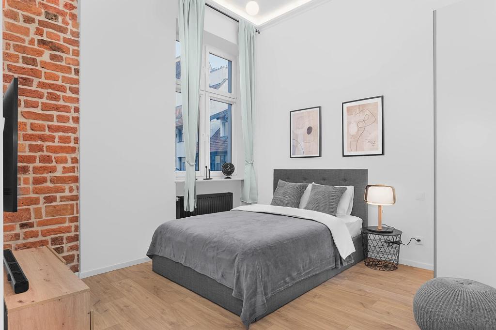 a white bedroom with a bed and a brick wall at Grey Panther Apartment in the Heart of Wroclaw in Wrocław