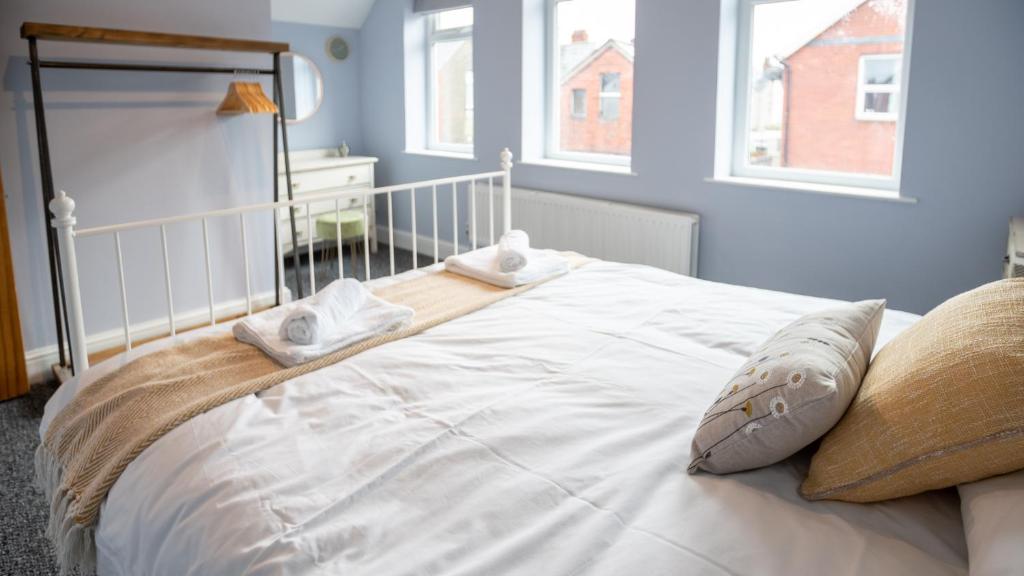 a large white bed in a room with windows at Lovely Coach House with Free Parking in Cardiff