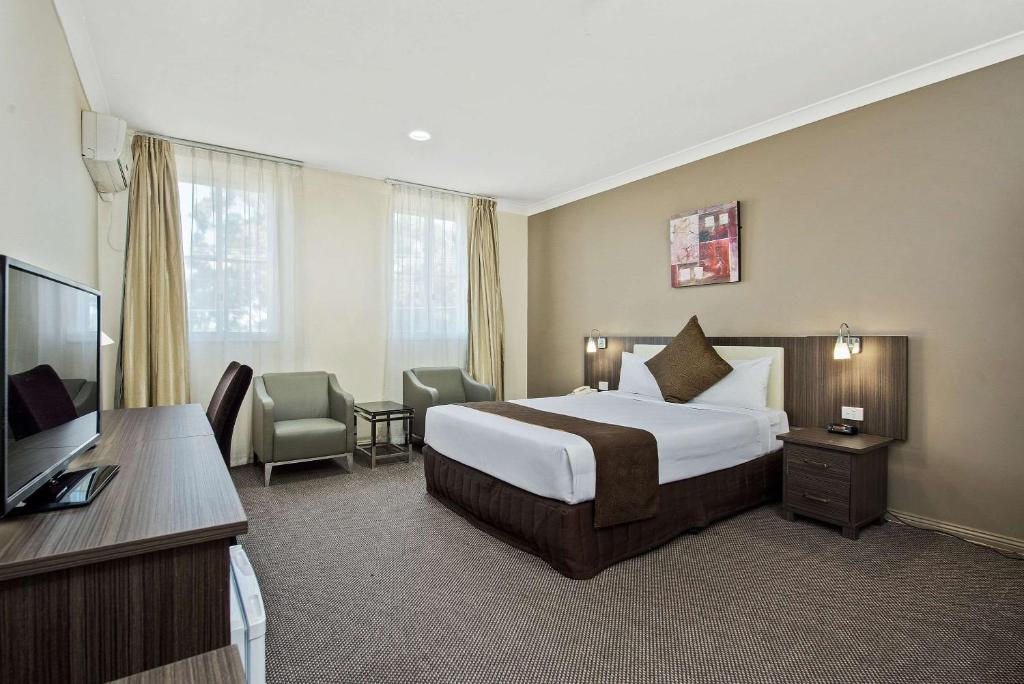 a hotel room with a bed and a flat screen tv at Comfort Hotel Dandenong in Dandenong