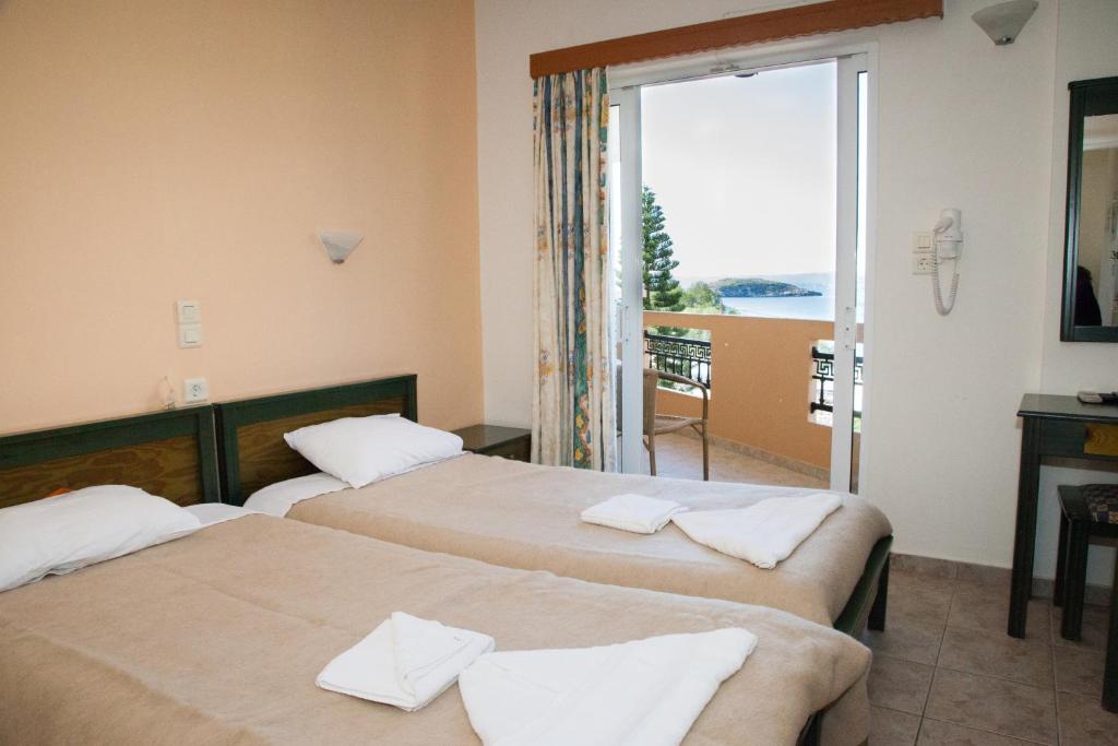 a hotel room with three beds and a balcony at Meandros in Almirida