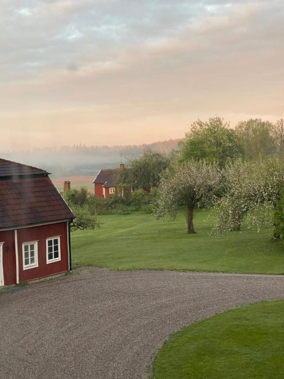 a red house with a gravel driveway next to a yard at Herrgårdsflygel mitt i Sörmland in Malmköping