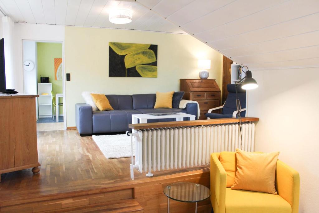 Ferienwohnung am Stemberg في ديتمولد: غرفة معيشة مع أريكة زرقاء وكراسي صفراء