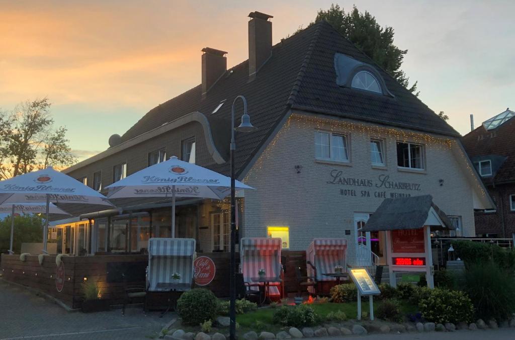 a building with chairs and umbrellas in front of it at Petersen's Landhaus in Scharbeutz