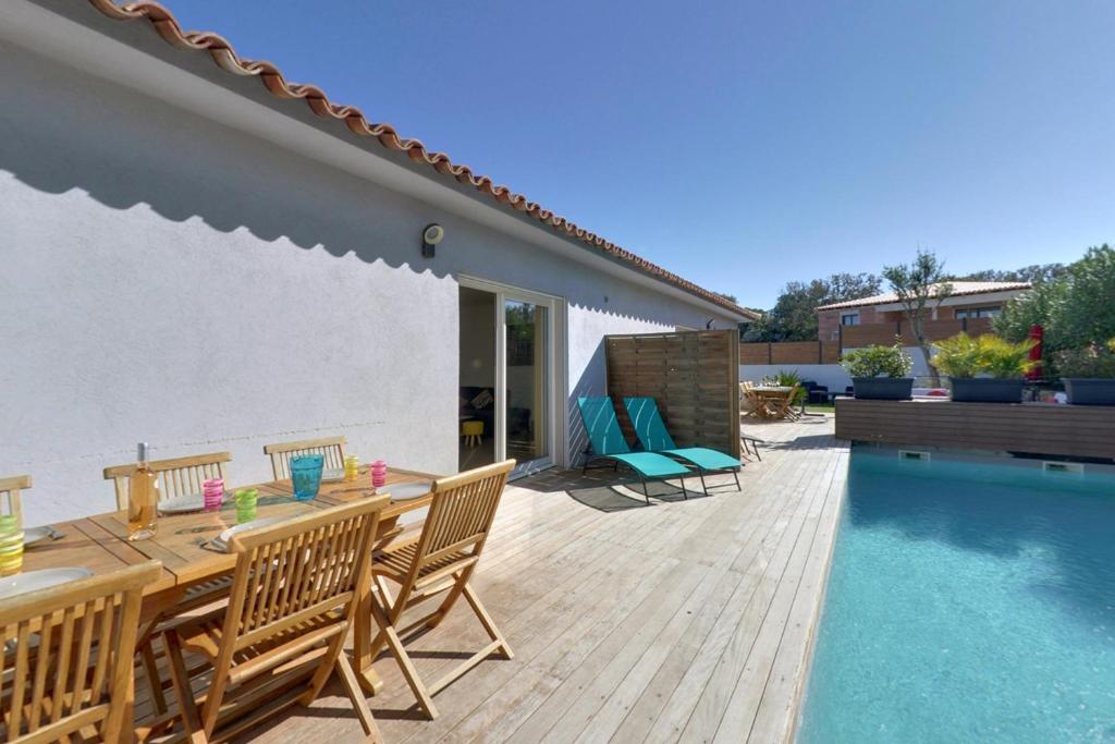 a patio with a wooden table and chairs next to a swimming pool at Villa Orethaga Piscine 10 pers porto Vecchio in Porto-Vecchio