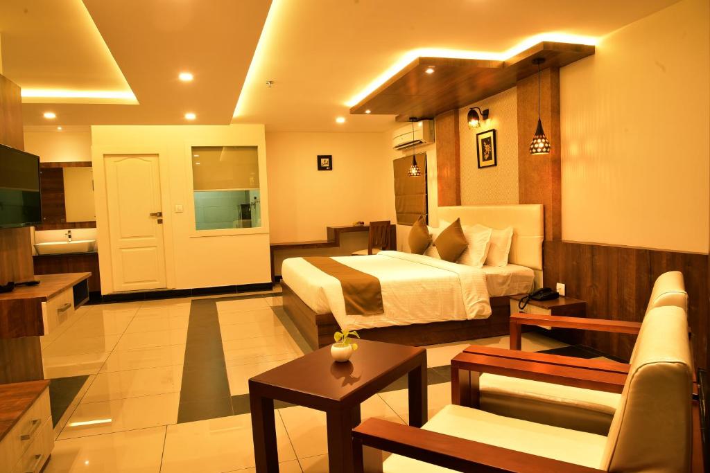 een hotelkamer met een bed en een woonkamer bij WHITE SUITE HOTEL in Kozhikode