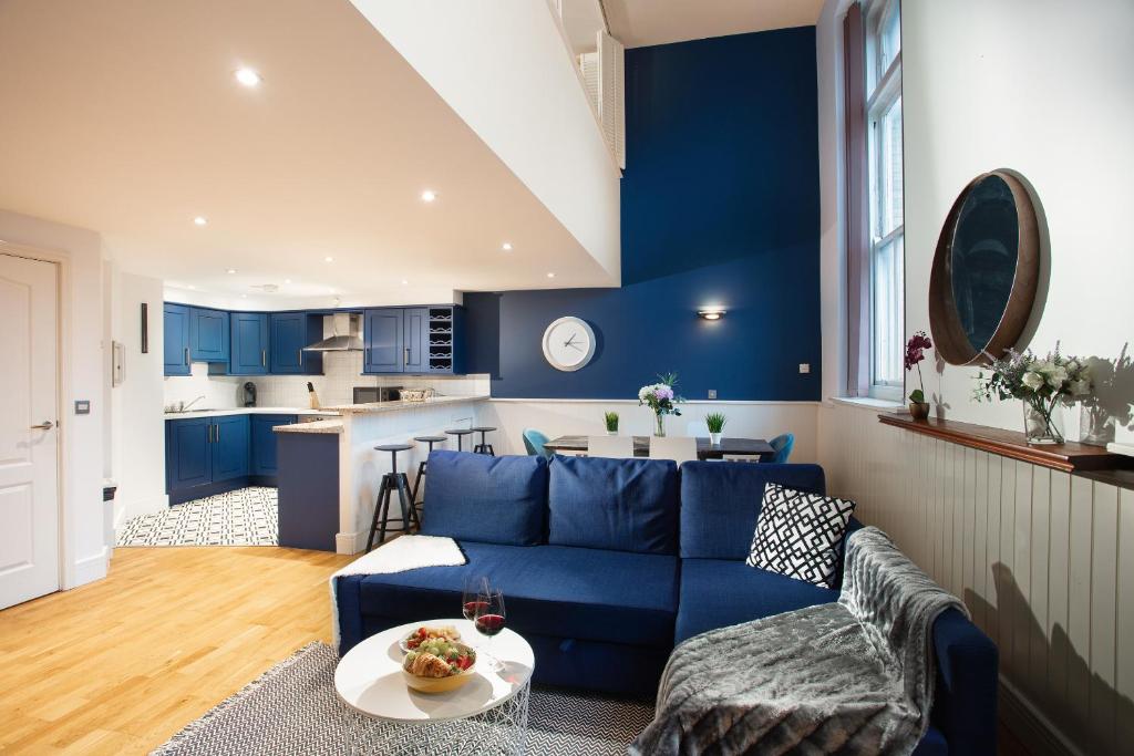 a living room with a blue couch and a kitchen at Plymouth Central Duplex Apartment - Private Parking - Sleeps 6 - Habita Property in Plymouth