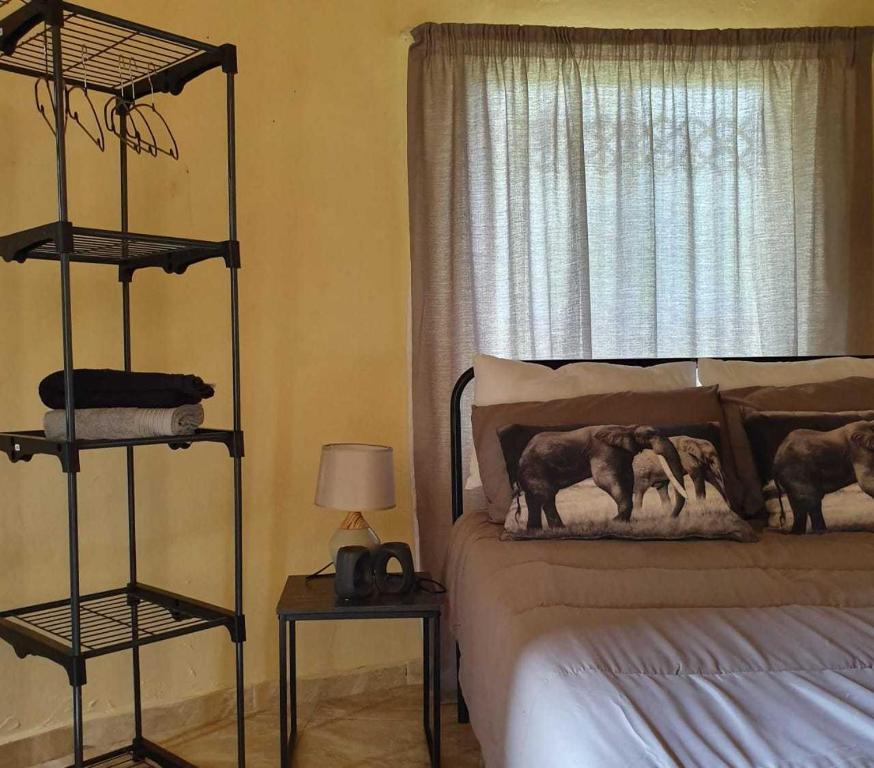 um quarto com uma cama e uma janela com duas almofadas de elefante em Rhumbini Lodge em Malamulele