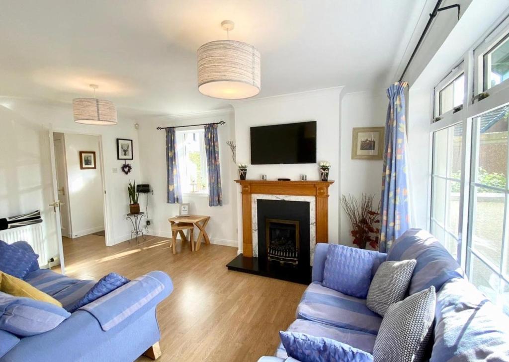 uma sala de estar com dois sofás azuis e uma lareira em Wellingtonia Court Apartment em Inverness