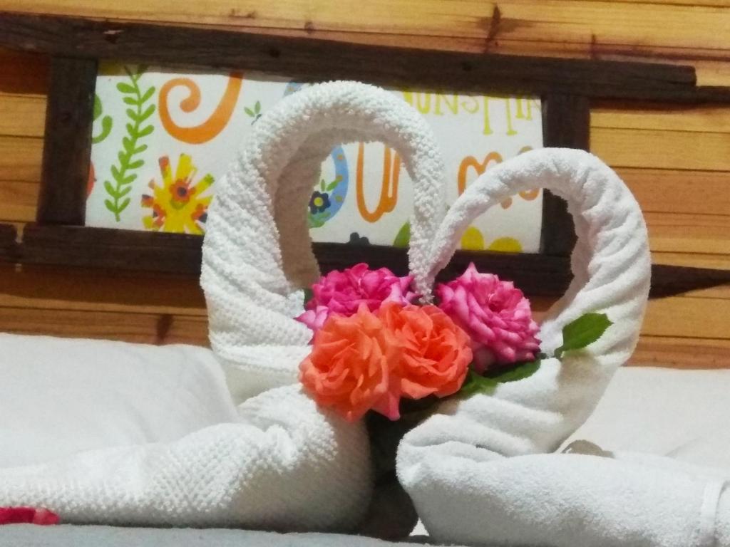 two white towels with flowers in them on a bed at Gaboto, solo se reserva con sena , entrar en contacto in Chuy