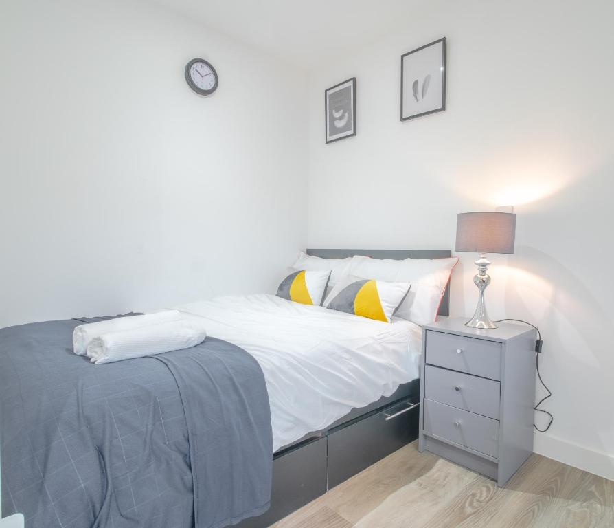 a white bedroom with a bed and a night stand at Modern Studio Serviced Apartments Sheffield City Centre - Netflix, WiFi, Digital TV in Sheffield