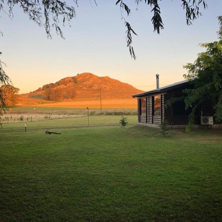 a house in a field with a mountain in the background at Complejo Cabañas Cerro Redondo in Tandil