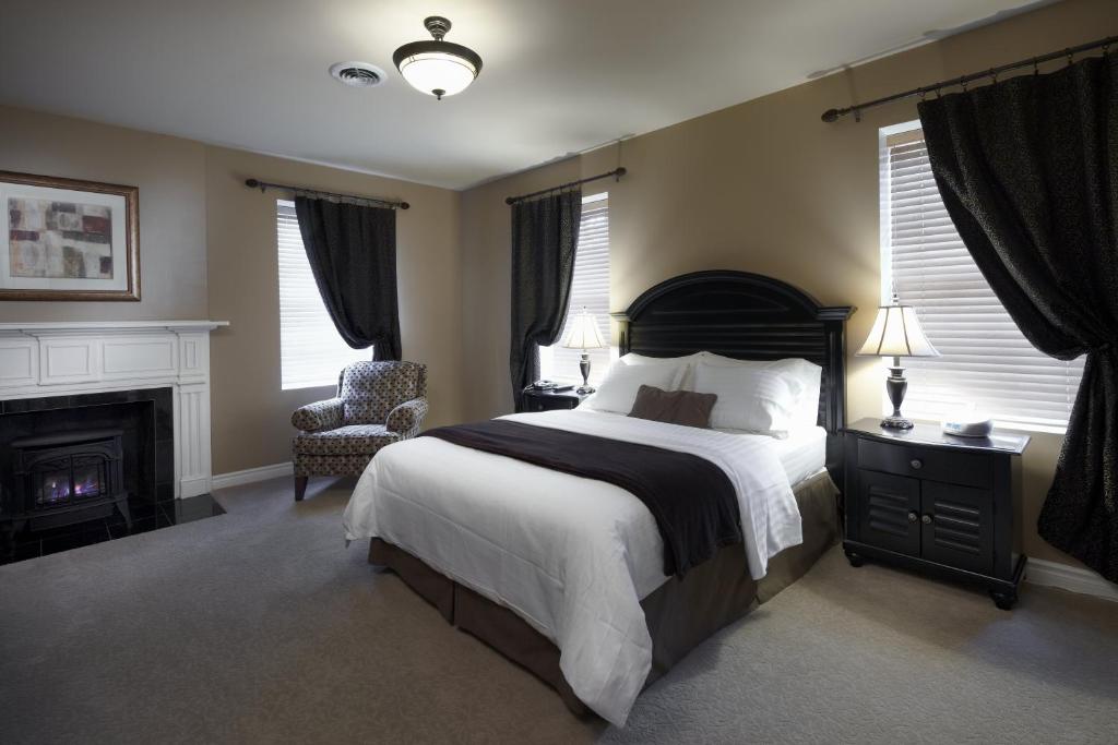 a bedroom with a bed and a chair and a fireplace at Greaves Sweet Escape in Niagara on the Lake