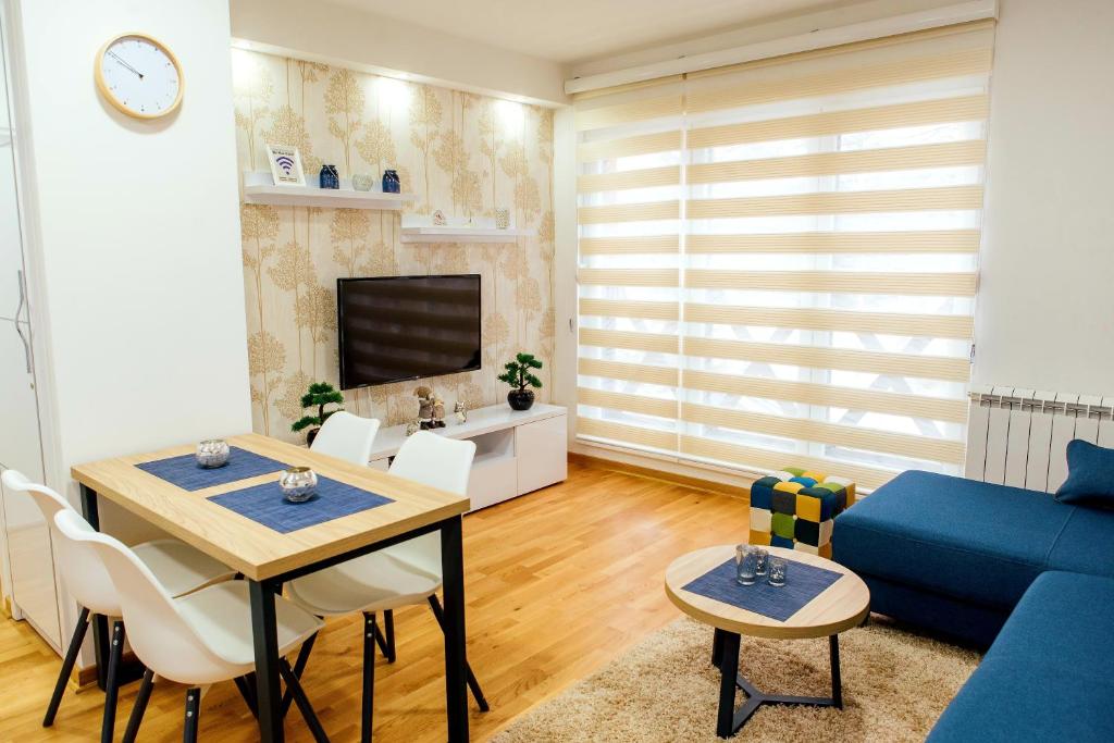 ein Wohnzimmer mit einem Tisch und einem blauen Sofa in der Unterkunft Apartman Happy day Divčibare in Divčibare