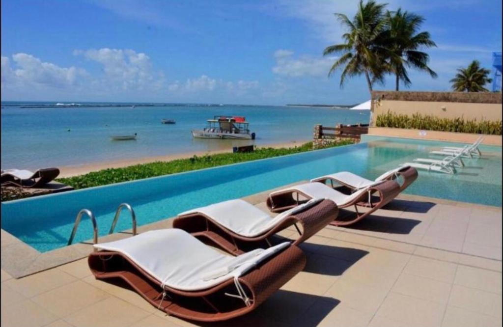 a group of lounge chairs sitting next to a swimming pool at Barra Bali Apartamento 06 - Paraíso à Beira Mar in Barra de São Miguel