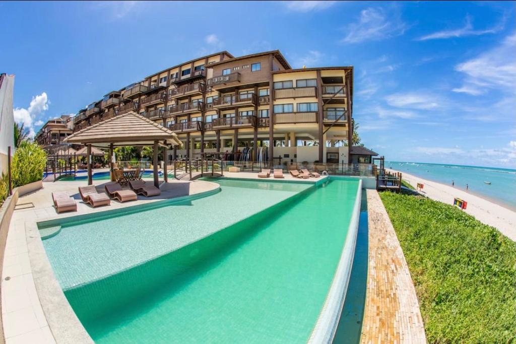 バーハ・デ・サン・ミゲウにあるBarra Bali Ap 06 - Paraíso à Beira Marのビーチのそばにスイミングプールがあります。