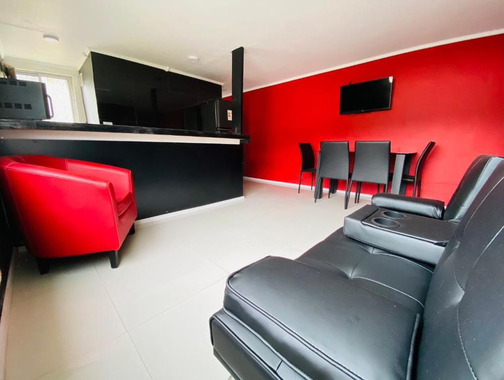 a waiting room with red walls and black chairs at Departamento cercano a Alameda y locales comerciales in Constitución