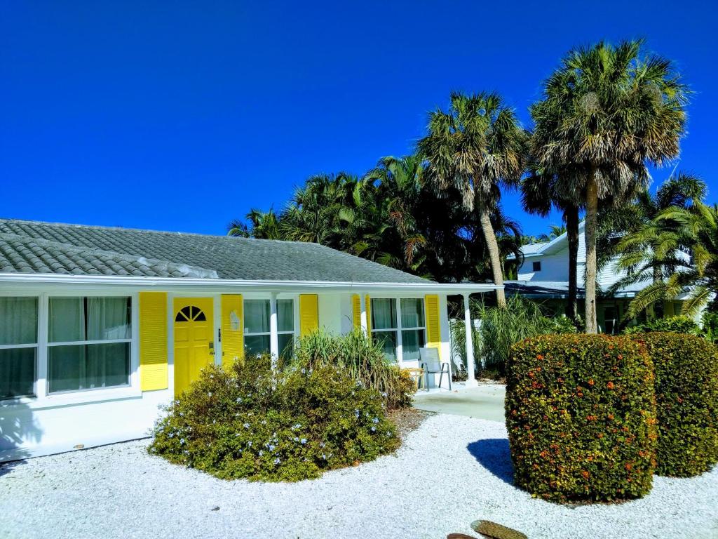 una casa gialla con palme di fronte di Steps from the Gulf of Mexico II a Holmes Beach