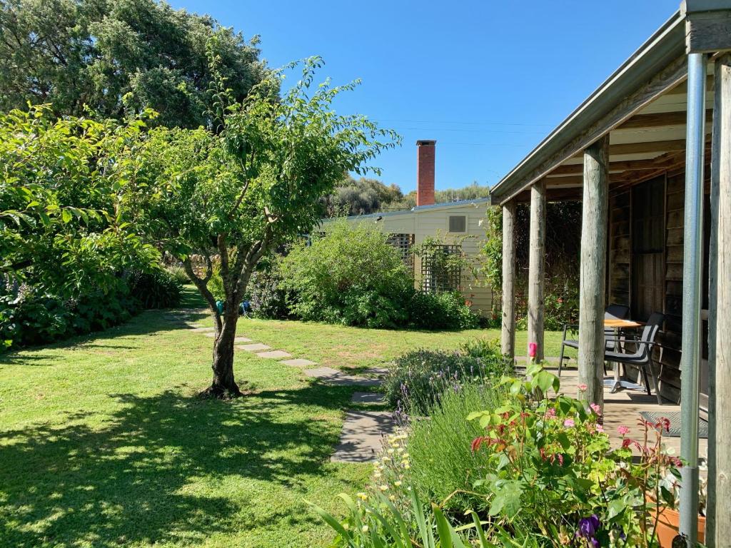 a garden with a tree and a house at Cherry Plum Cottages in Port Fairy