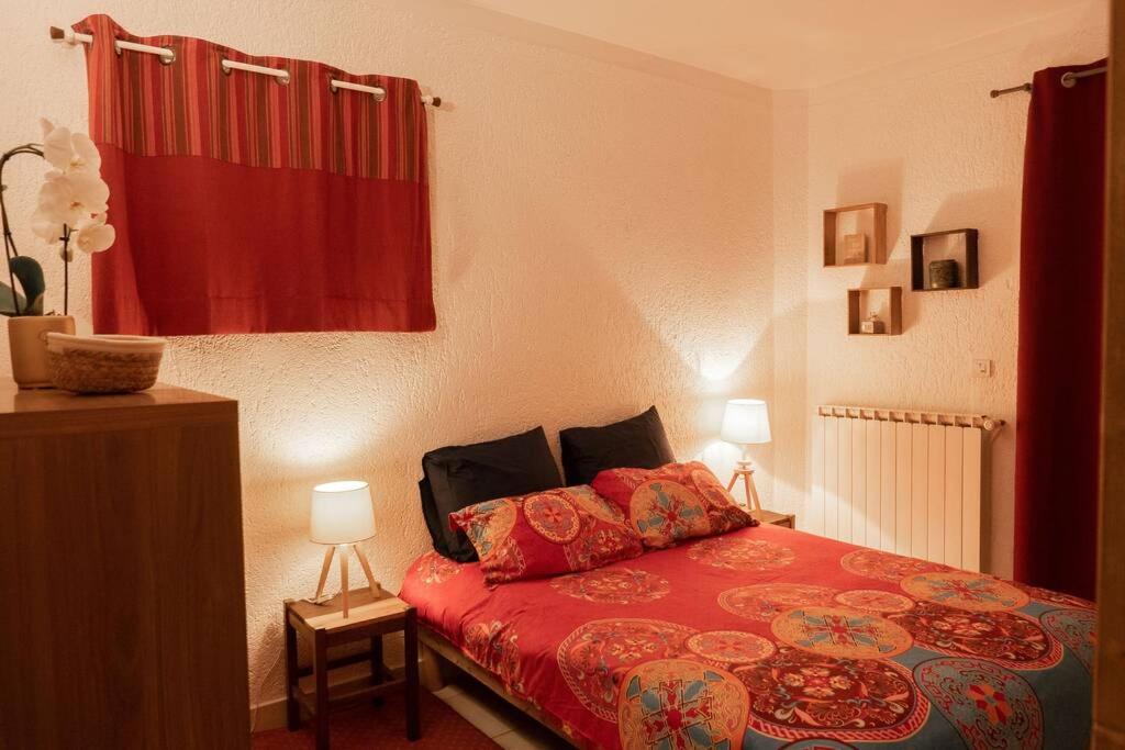 a bedroom with a bed with a red comforter at Gites de la Lurette - agréable T2 indépendant dans cadre calme et verdoyant in Cazilhac